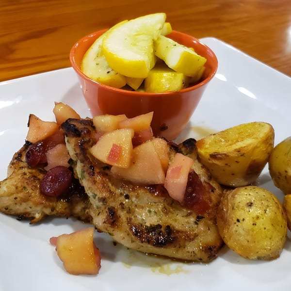 Grilled chicken with fruit salsa, roasted potatoes, and a side of yellow squash.