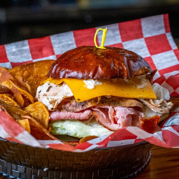 A Water Tower Grille sandwich with turkey, ham, cheese, and lettuce, served with chips in a basket.
