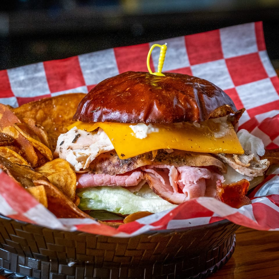 A Water Tower Grille sandwich with turkey, ham, cheese, and lettuce, served with chips in a basket.